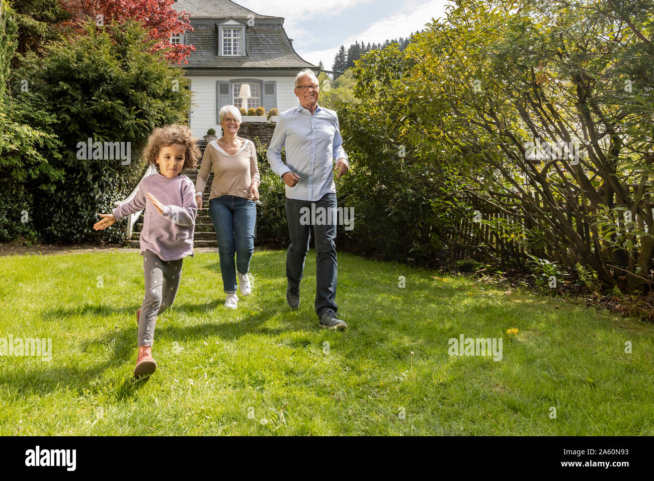 Happy grandson with grandparents running in garden Stock Photo
