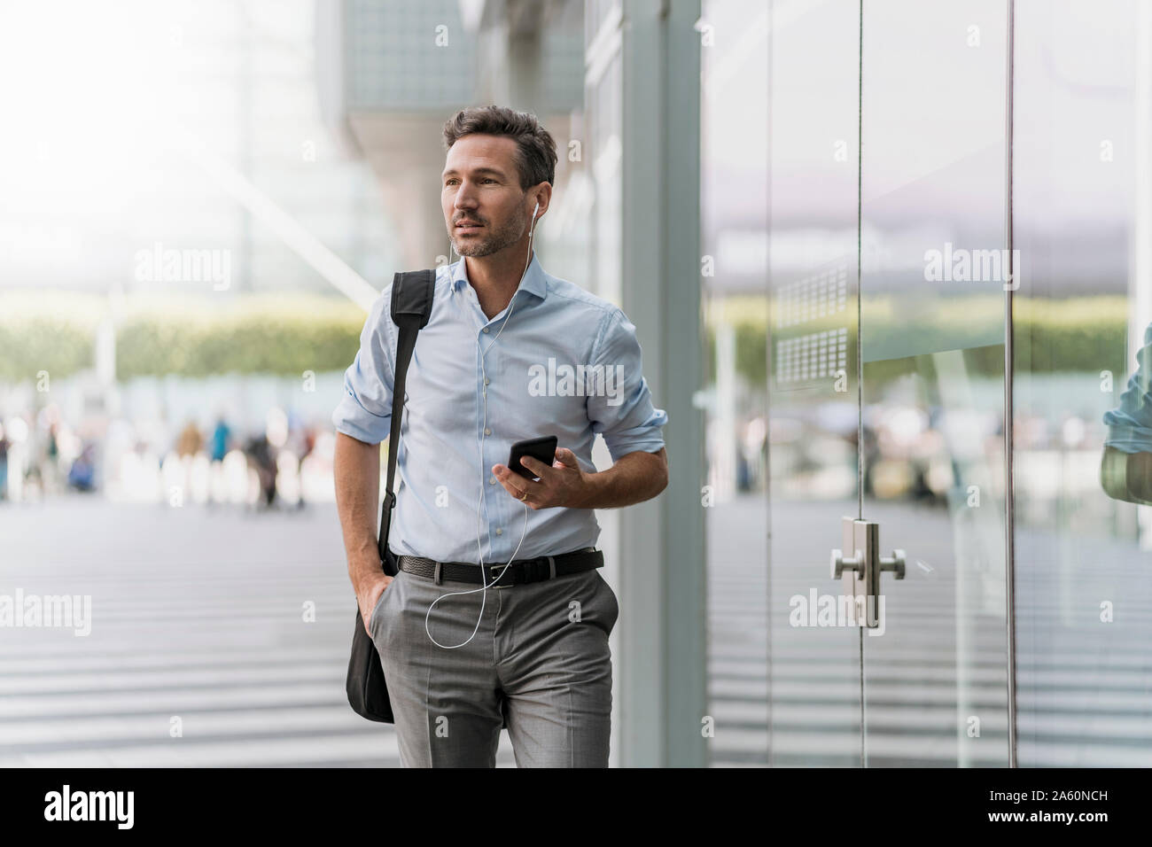 Businessman with cell phone and earphones on the go Stock Photo