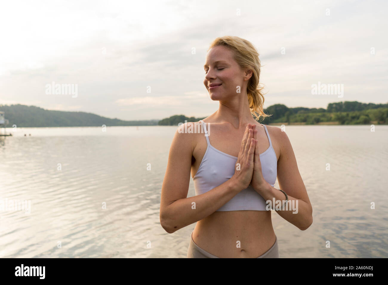 Young woman with folded hands at a lake Stock Photo