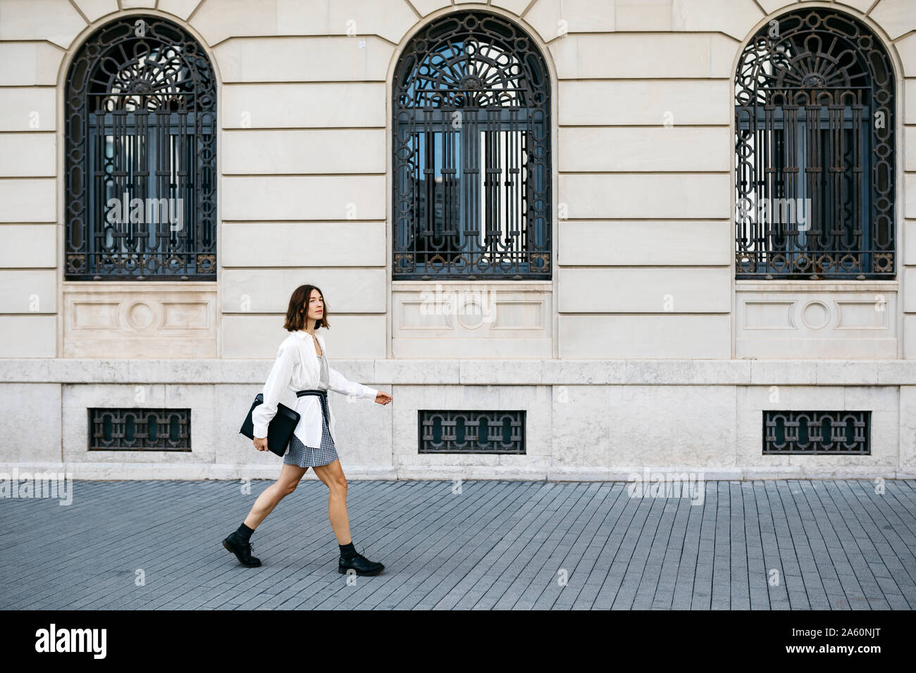 Well dressed woman carrying folder, walking in the city Stock Photo