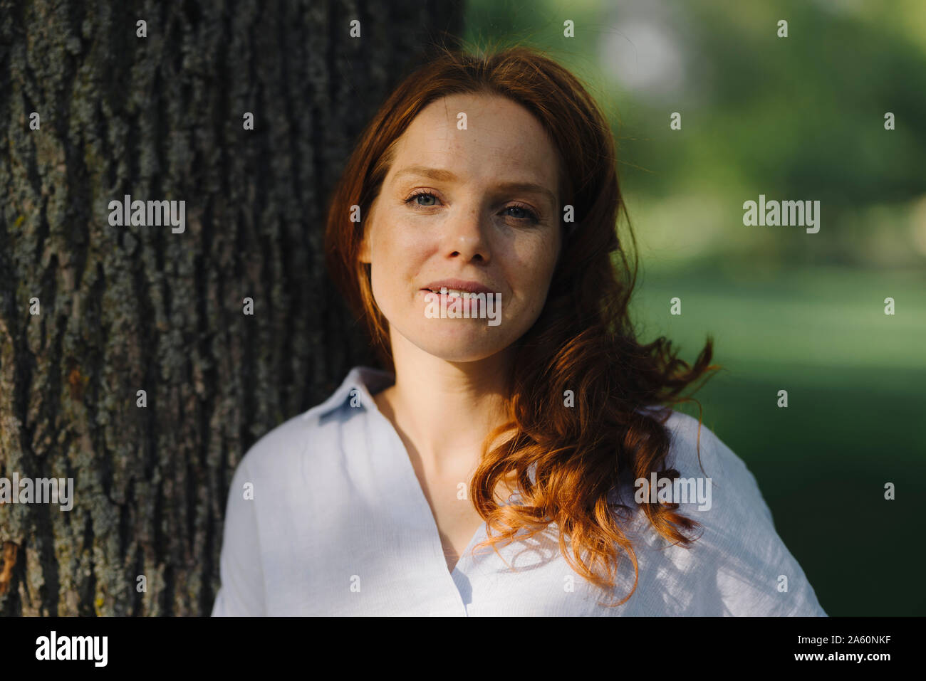 Portrait of redheaded woman at tree in a park Stock Photo - Alamy