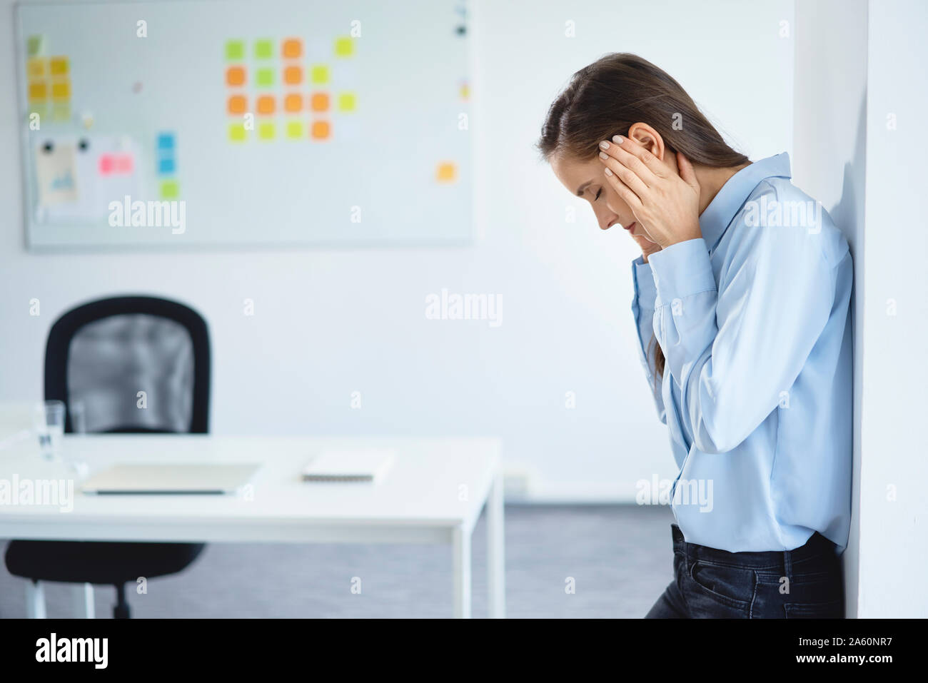 Young businesswoman suffering from headache in office Stock Photo