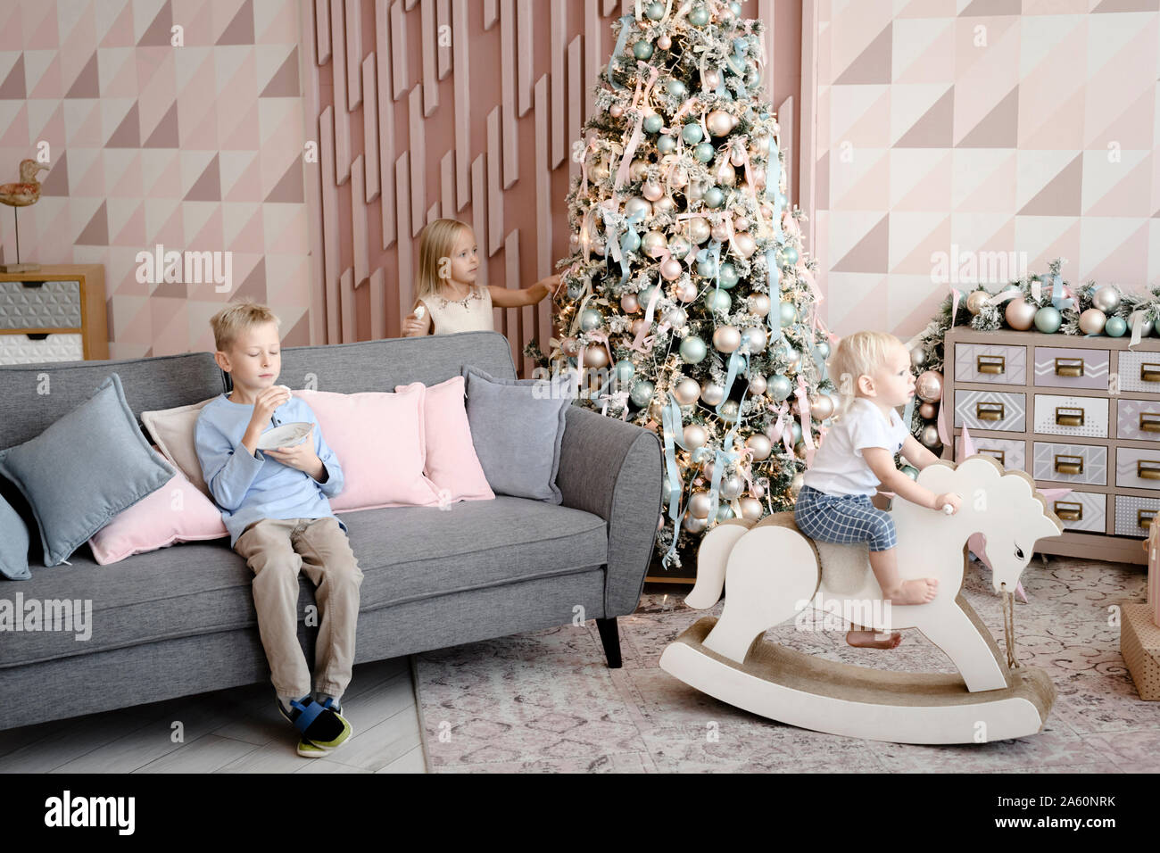 Three children playing and eating cookies in the living room at Christmas time Stock Photo