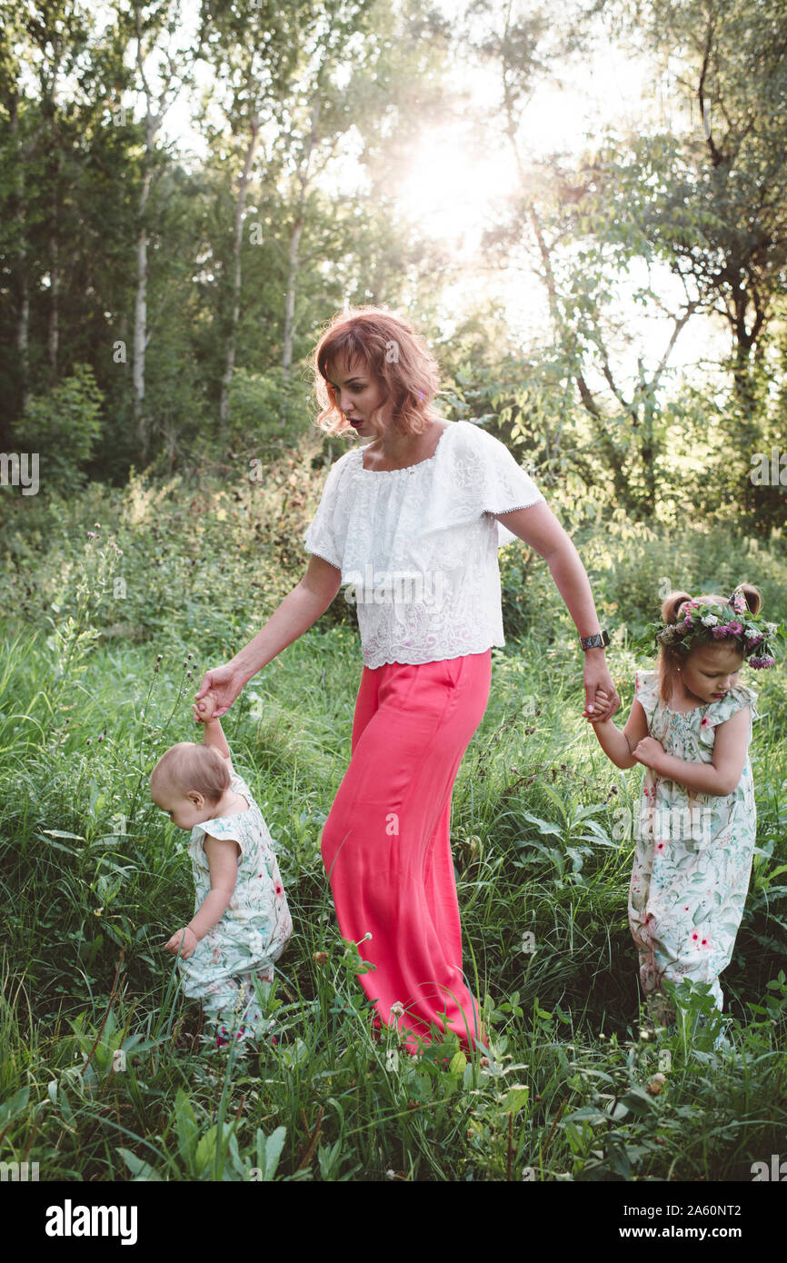 Mother with two daughters walking in a meadow Stock Photo