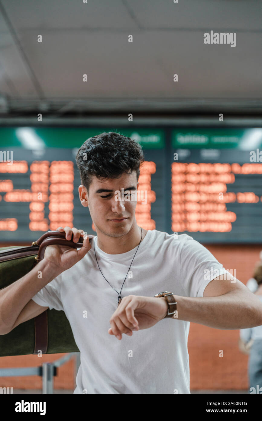 Young man checking the time at train station Stock Photo