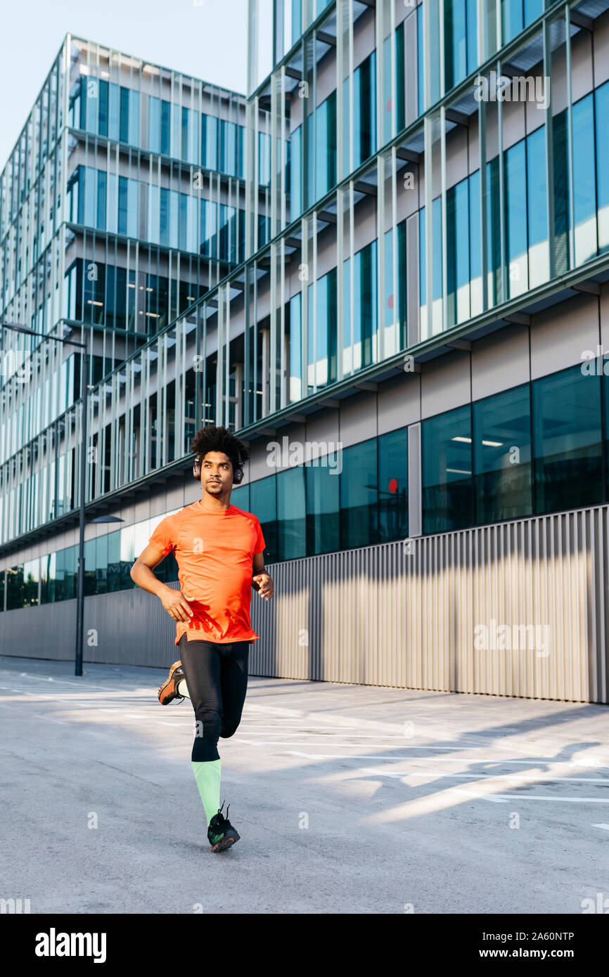 Young man jogging in the city, listening to music Stock Photo