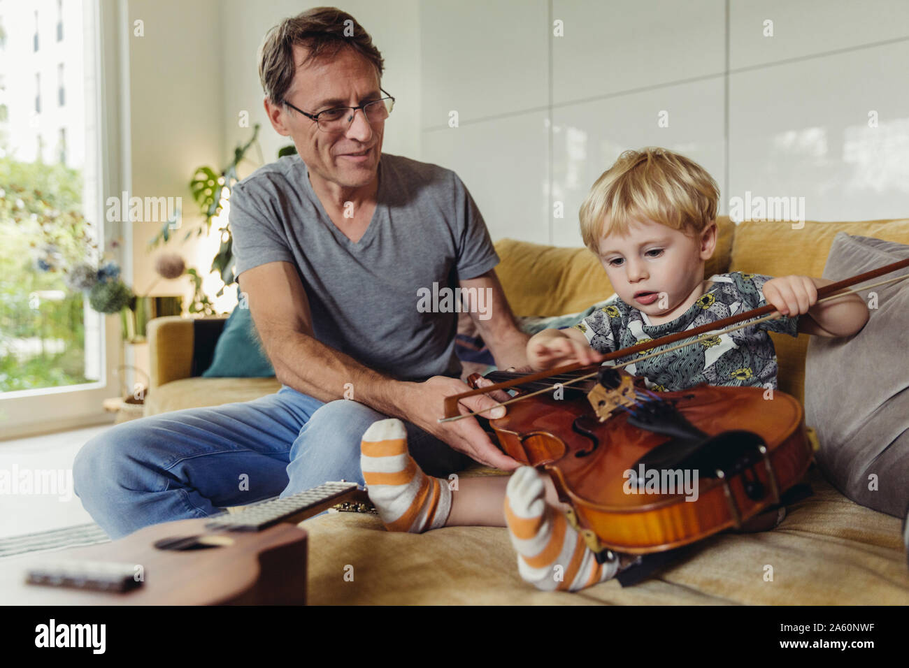 Portrait of toddler testingviolin while his father watching Stock Photo