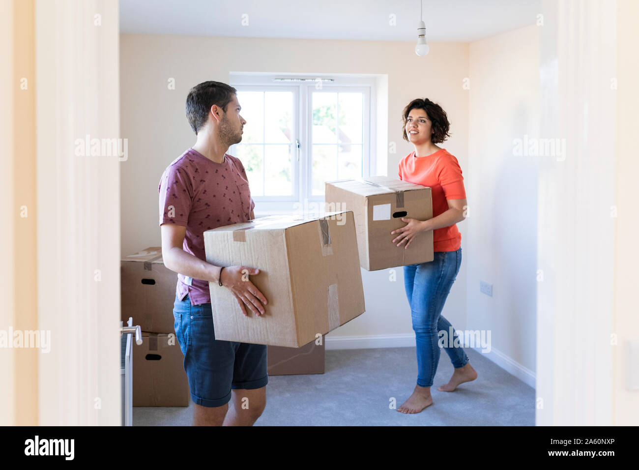 Couple moving into new home carrying cardboard boxes Stock Photo - Alamy