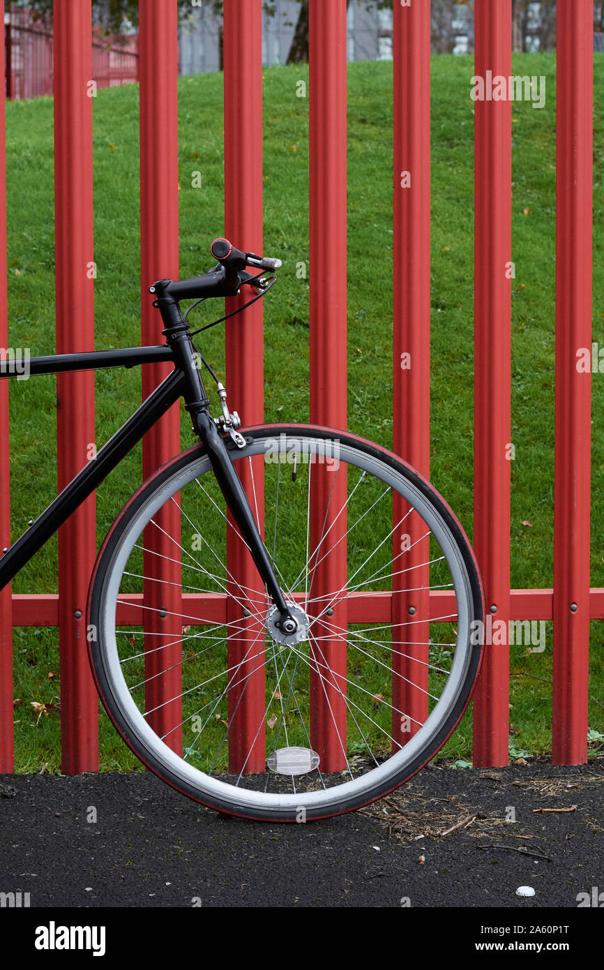 Bicycle parked on road by fence in park Stock Photo