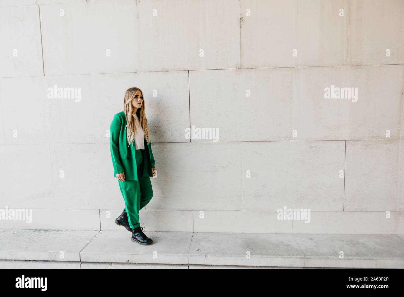 Blond young woman wearing green pantsuit outdoors Stock Photo