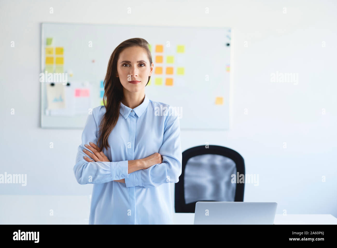 Portrait of confident businesswoman looking at camera with crossed arms in office Stock Photo