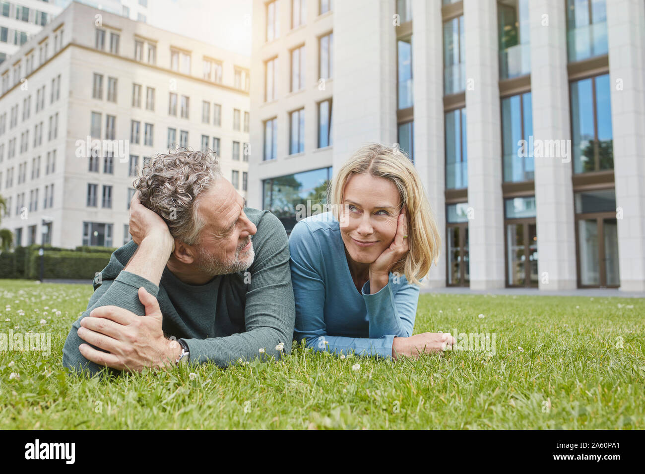 Relaxed mature couple lying on lawn in the city Stock Photo