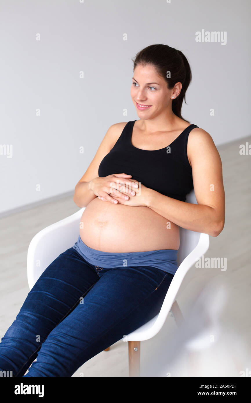Young pregnant woman sitting on chair and is thinking about the