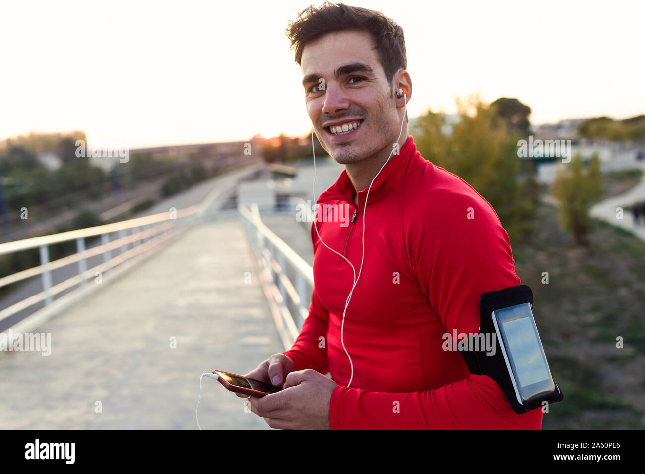 Jogger with smartphone in arm pocket, holding smartphone and looking at camera Stock Photo