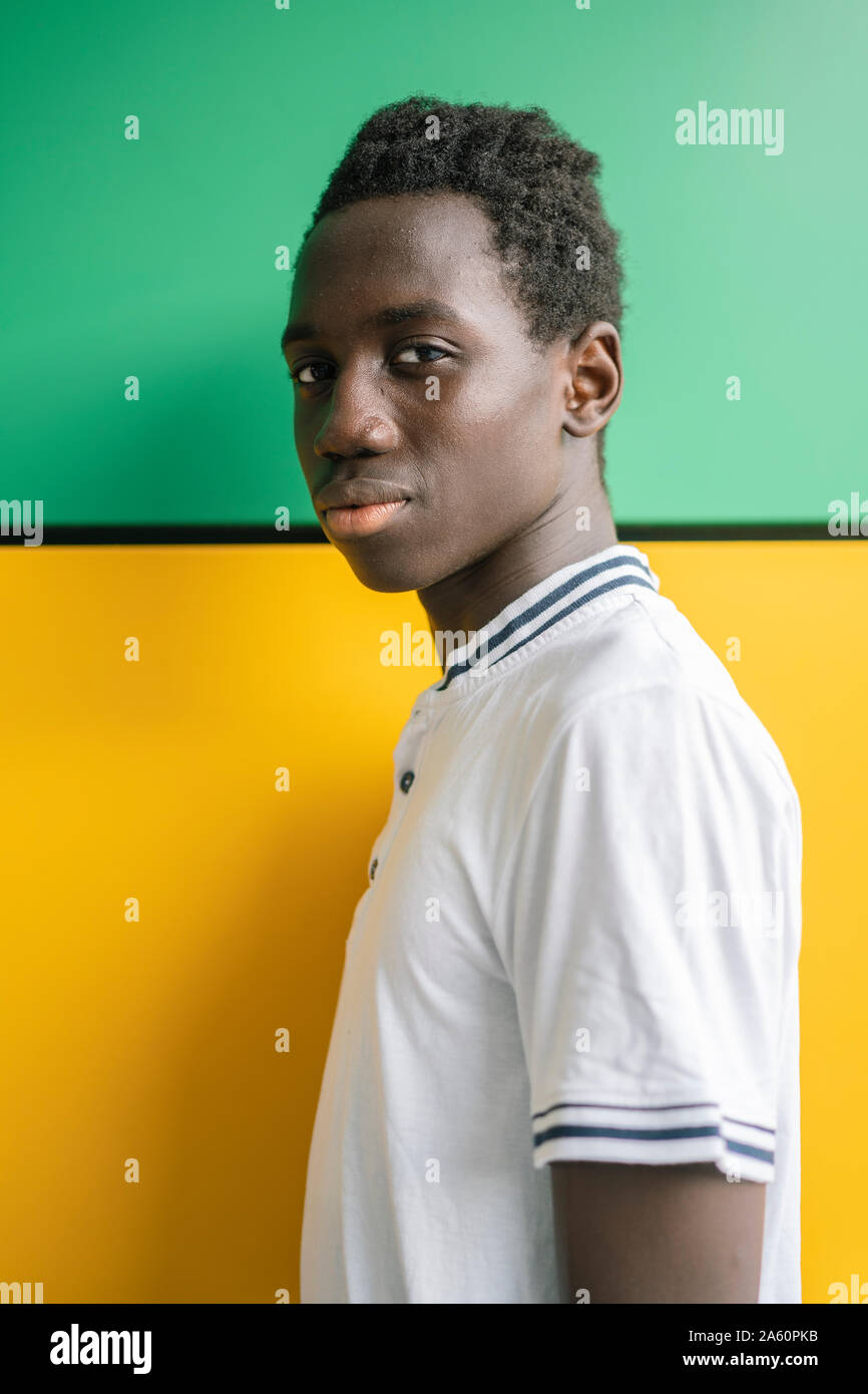 Portrait of teenage boy in front of green and yellow wall Stock Photo