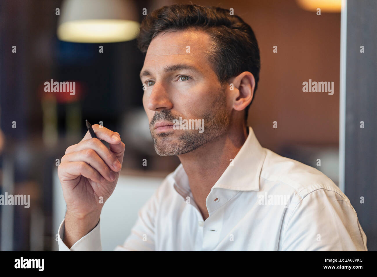 Portrait of thoughtful businessman holding pen Stock Photo