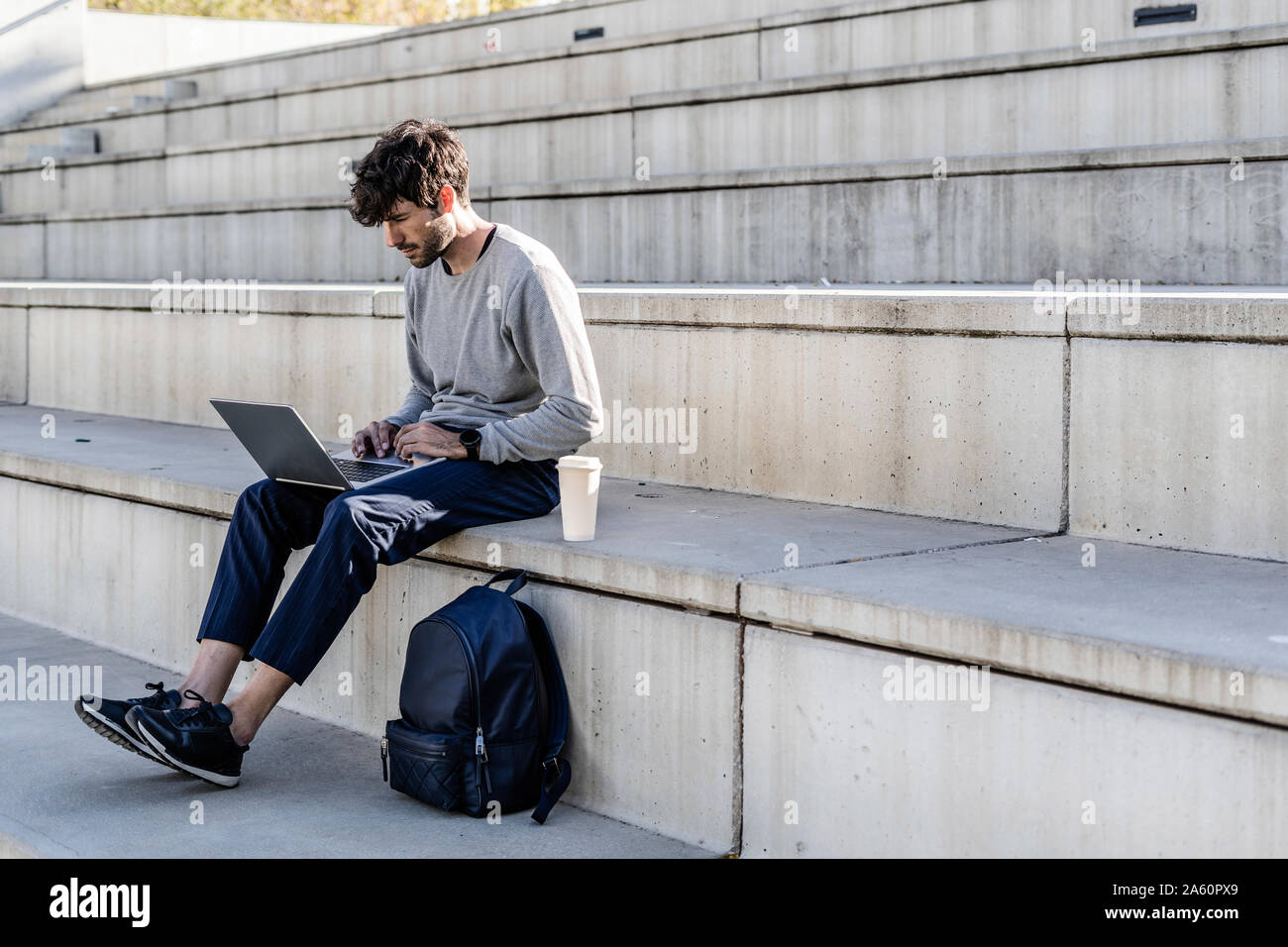 Man sitting on outdoor stairs using laptop Stock Photo