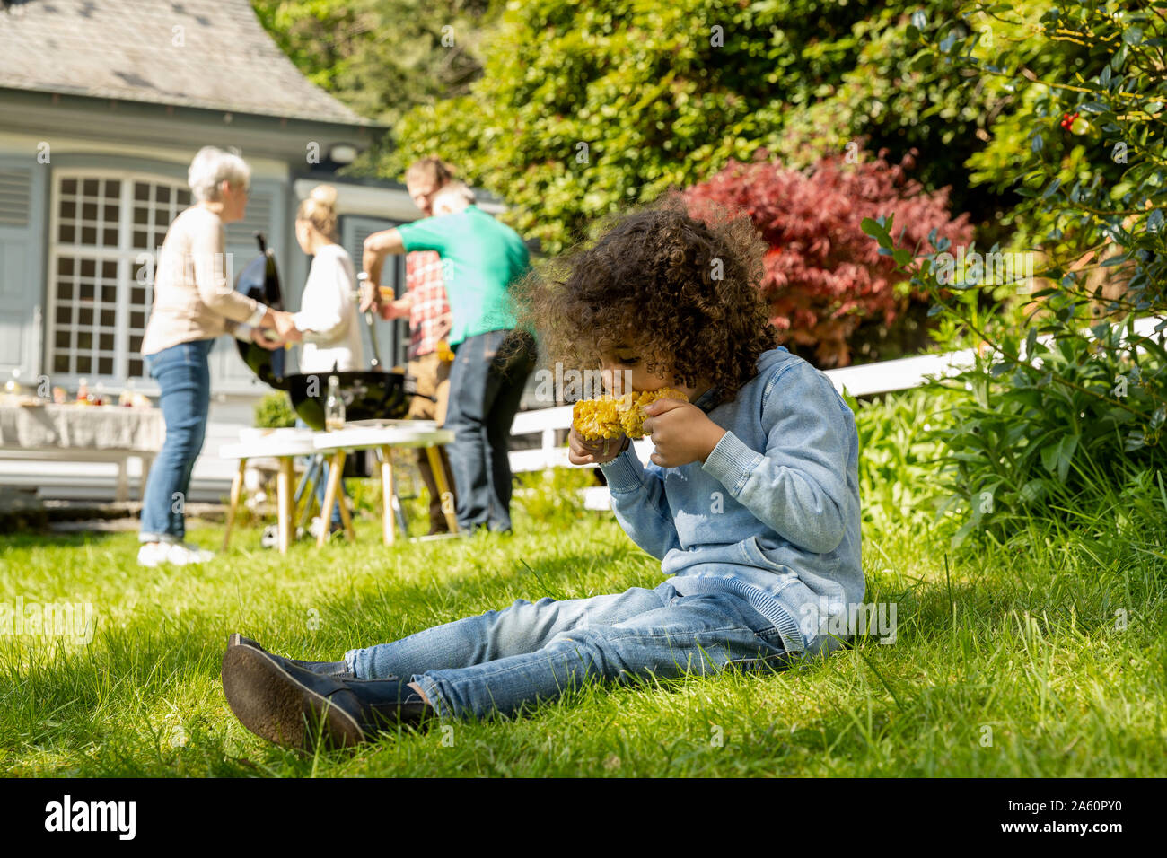 Boy eating a corn cob on a family barbecue in garden Stock Photo