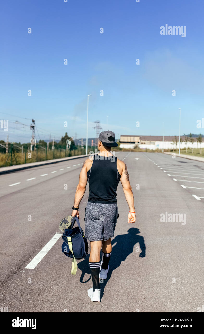 Sporty young man with backpack walking on a road Stock Photo