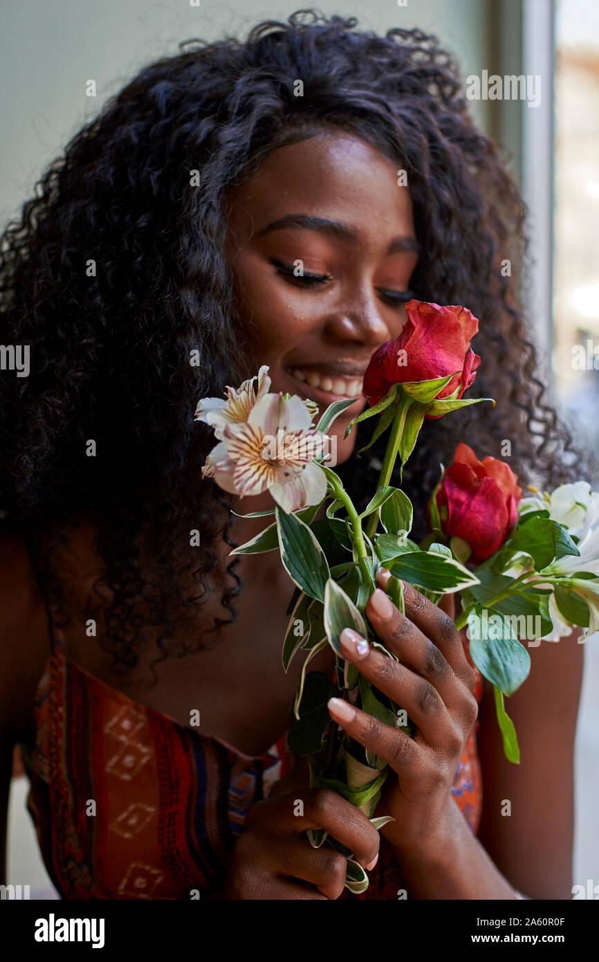 Portrait of young African woman  smelling flowers and smiling in a cafe Stock Photo