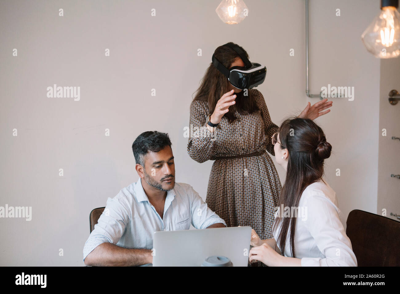 Colleagues working in office testing VR simulator - Stock Image