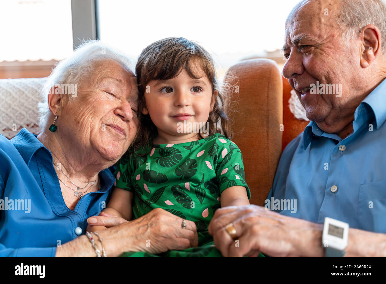 Grandparents spending time with the granddaughter in living room Stock Photo