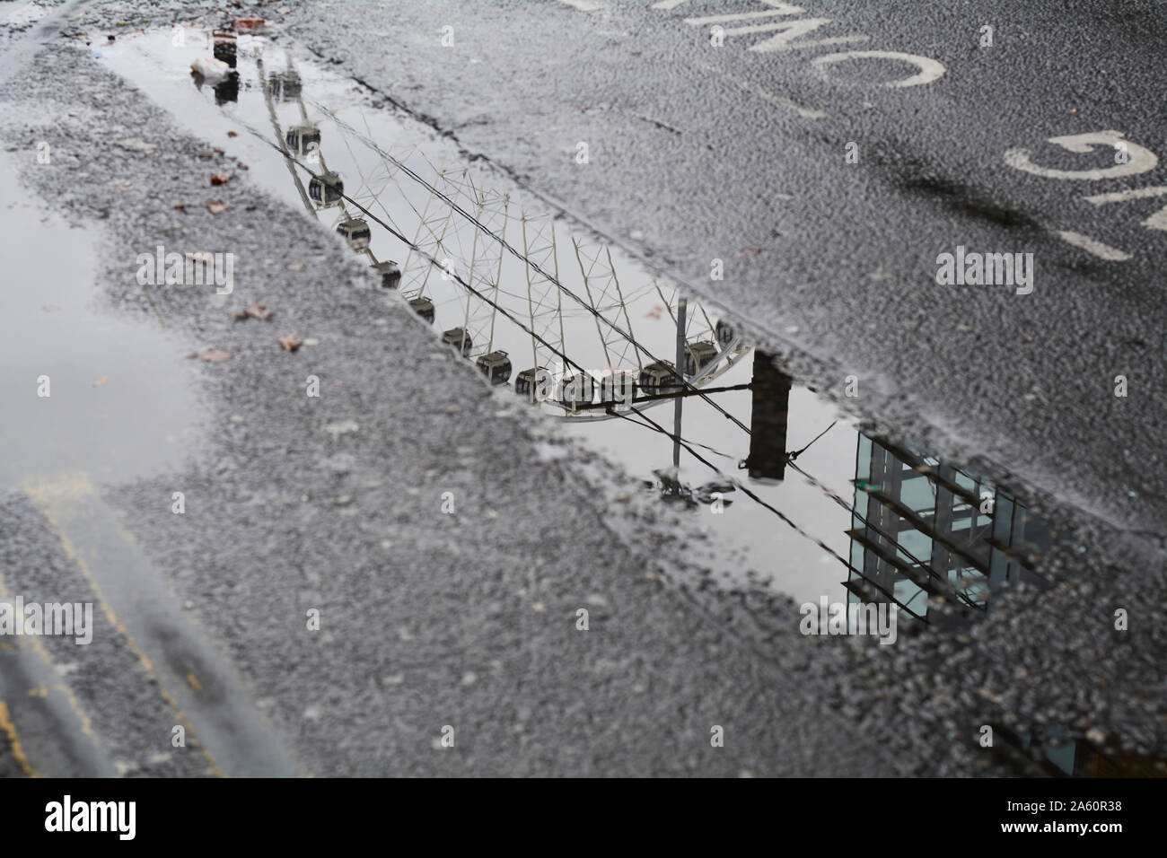 High angle view of Ferris wheel reflecting on puddle during rainy ...