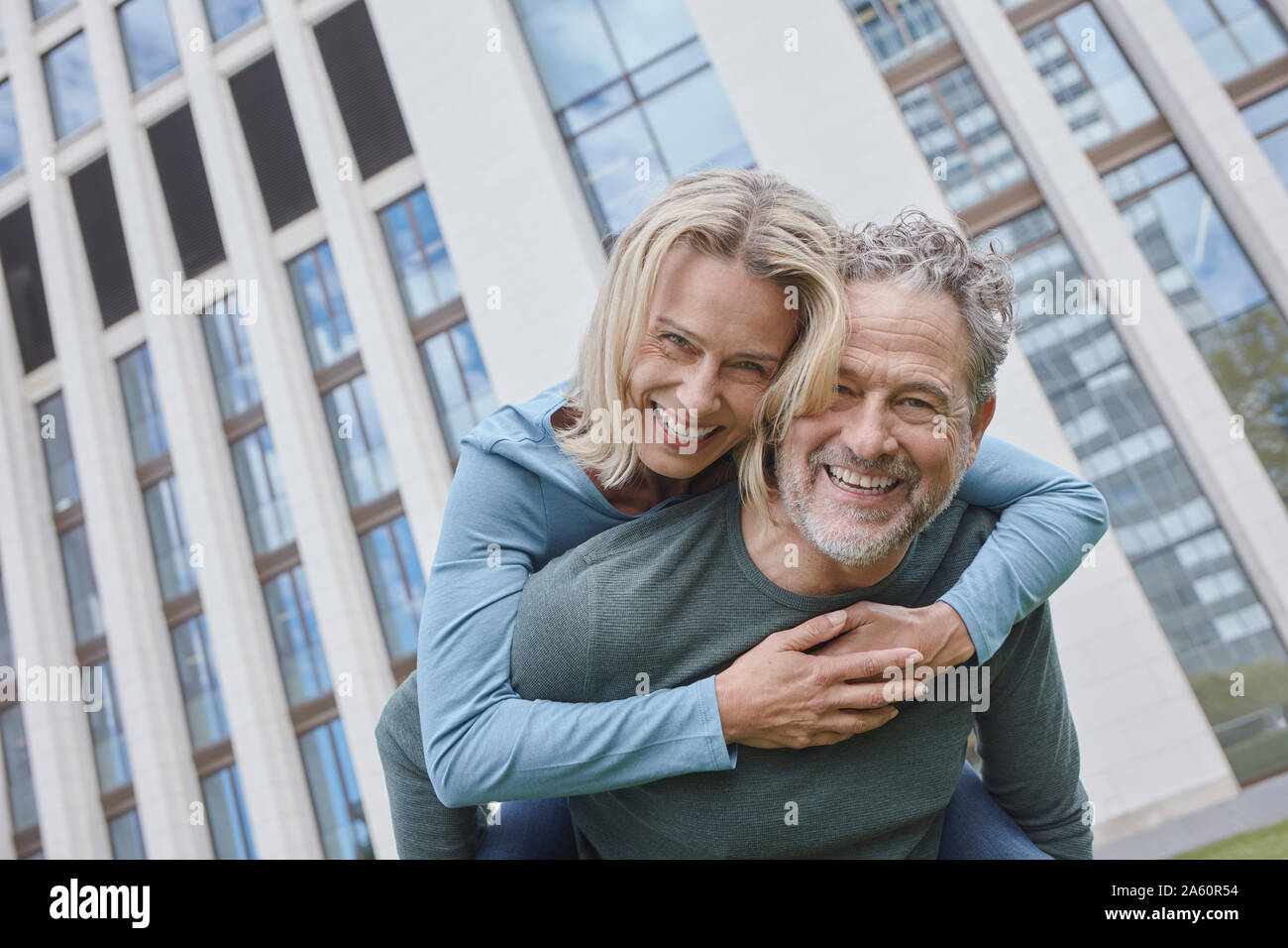 Happy mature man carrying woman piggyback in the city Stock Photo