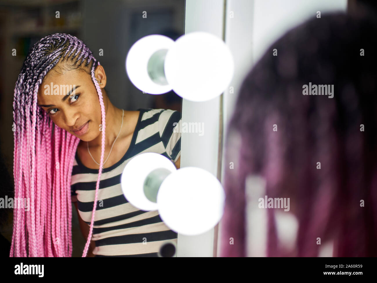 Content young woman with pink braids looking at her mirror image Stock Photo