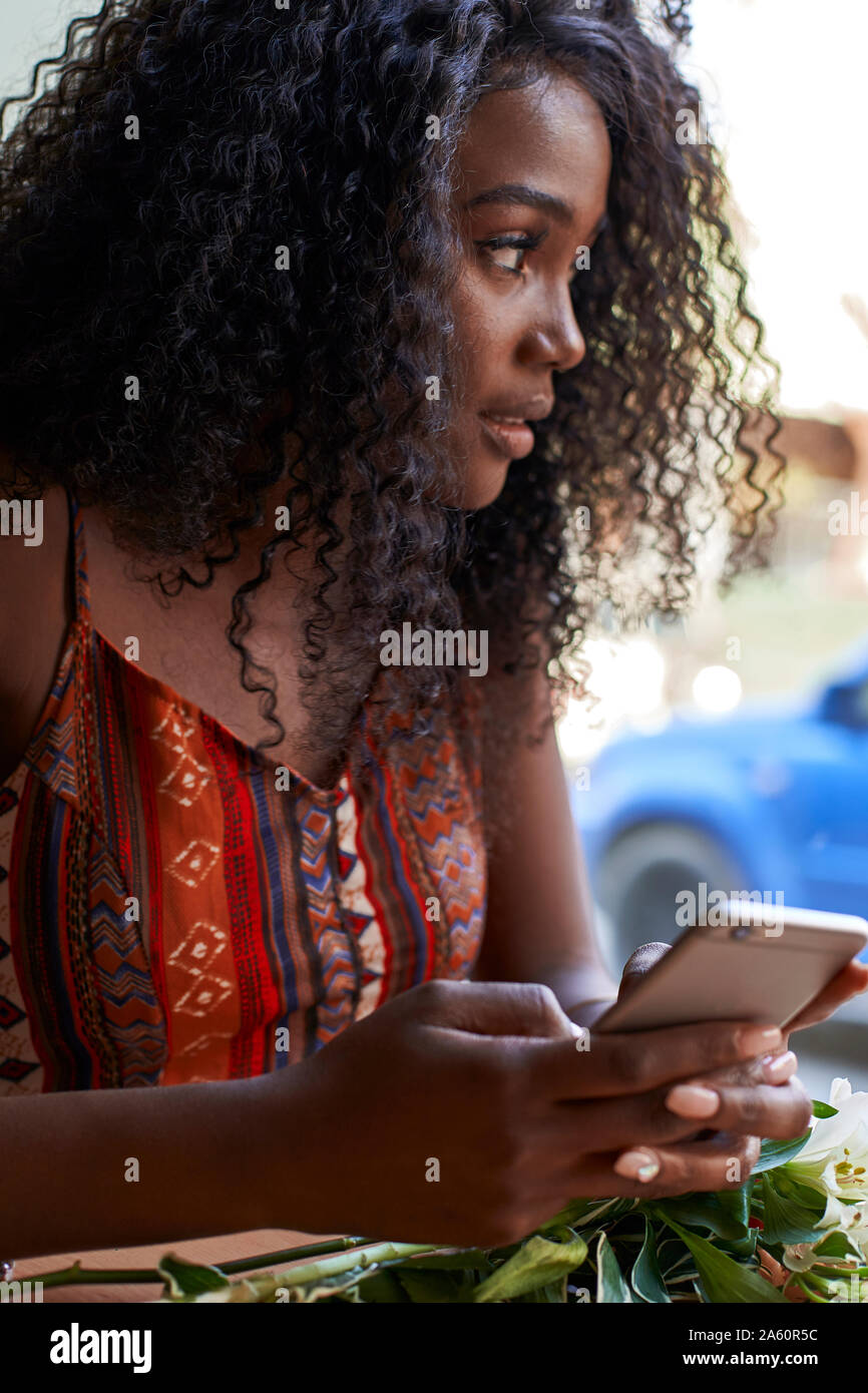 Portrait of young African woman in a cafe, checking her smartphone Stock Photo