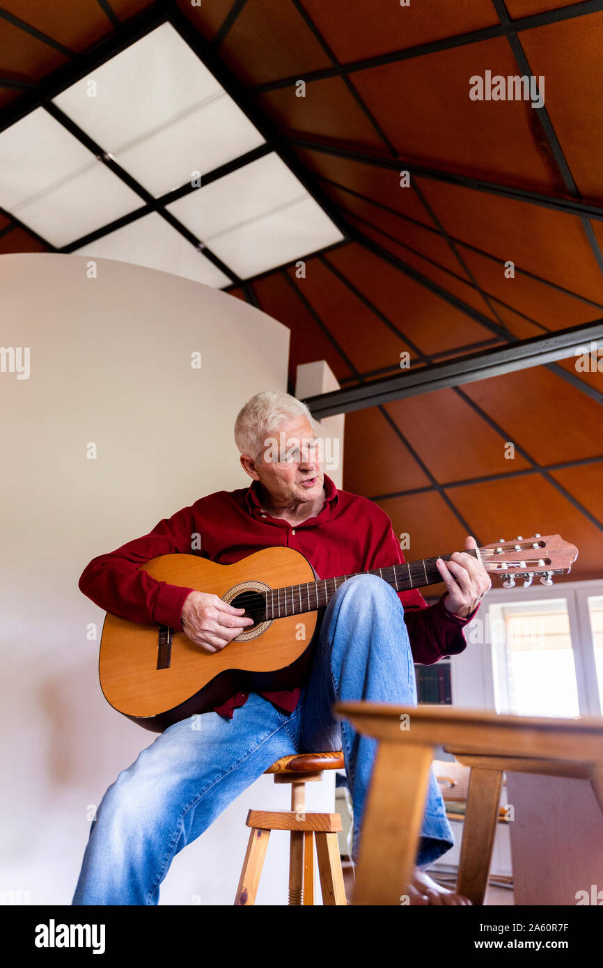 Senior man playing guitar at home Stock Photo