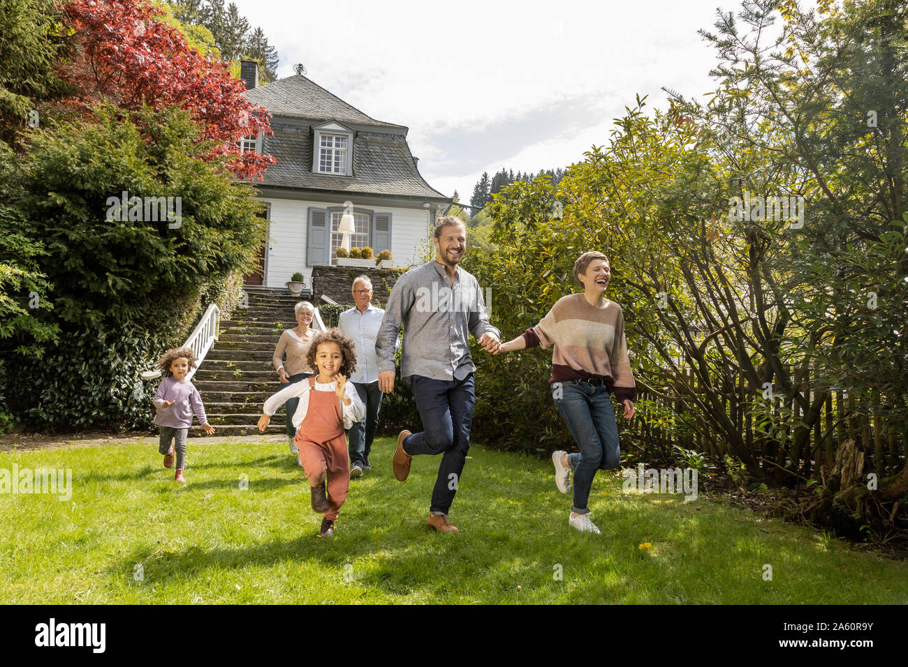 Happy extended family running in garden of their home Stock Photo