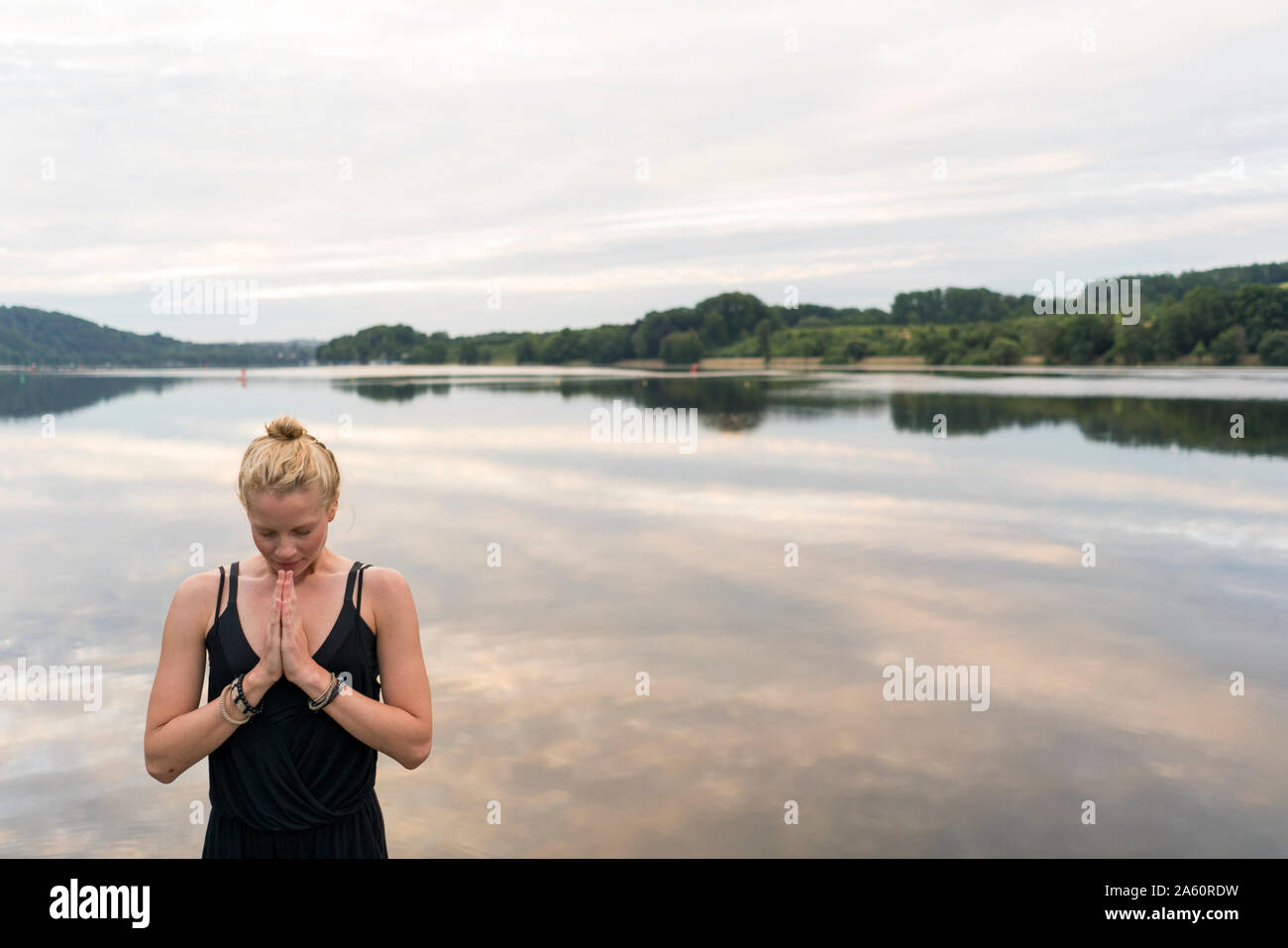 Young woman with folded hands at a lake Stock Photo