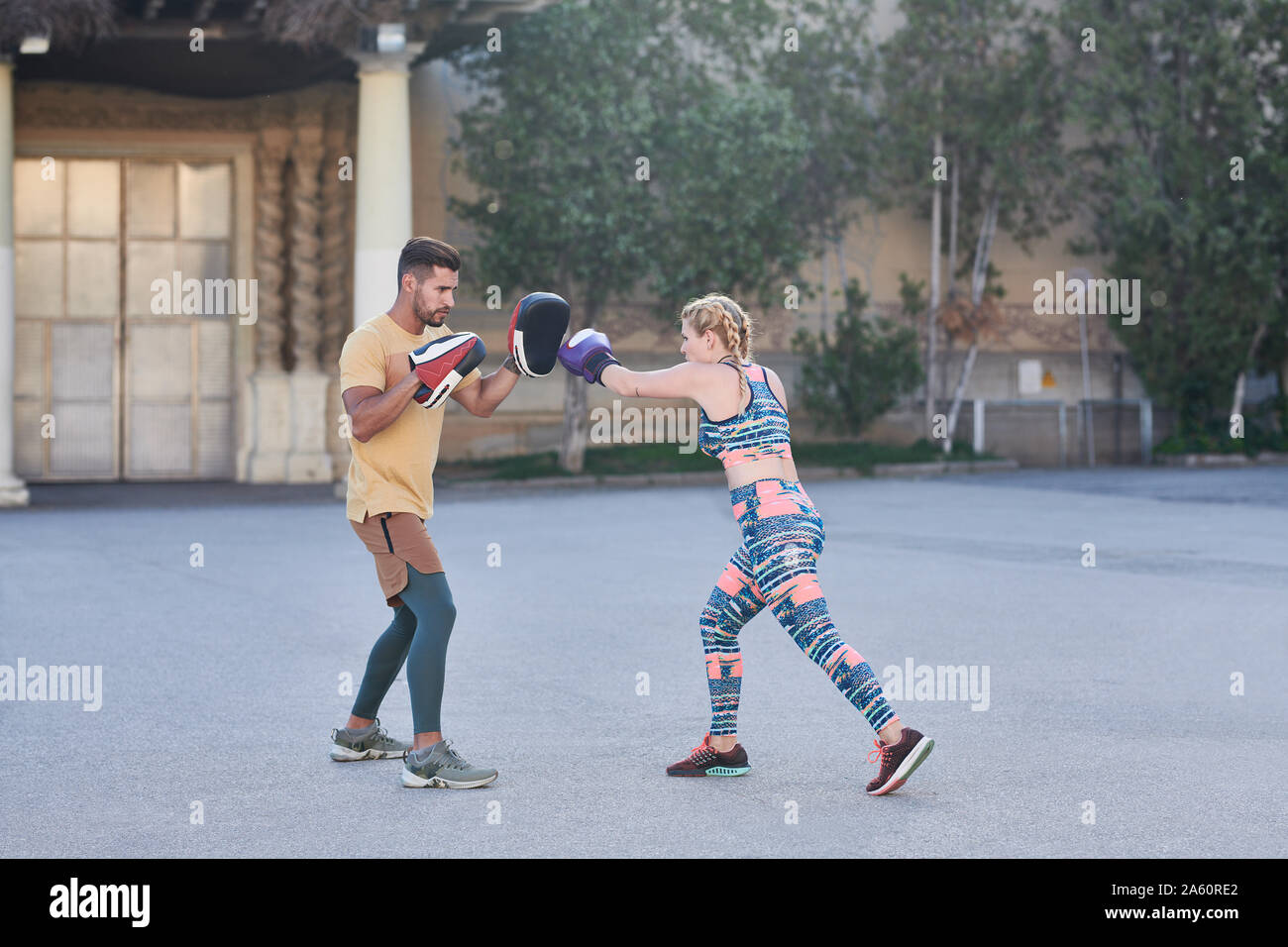 Fitness coach practicing boxing class with young woman outdoors in the city Stock Photo