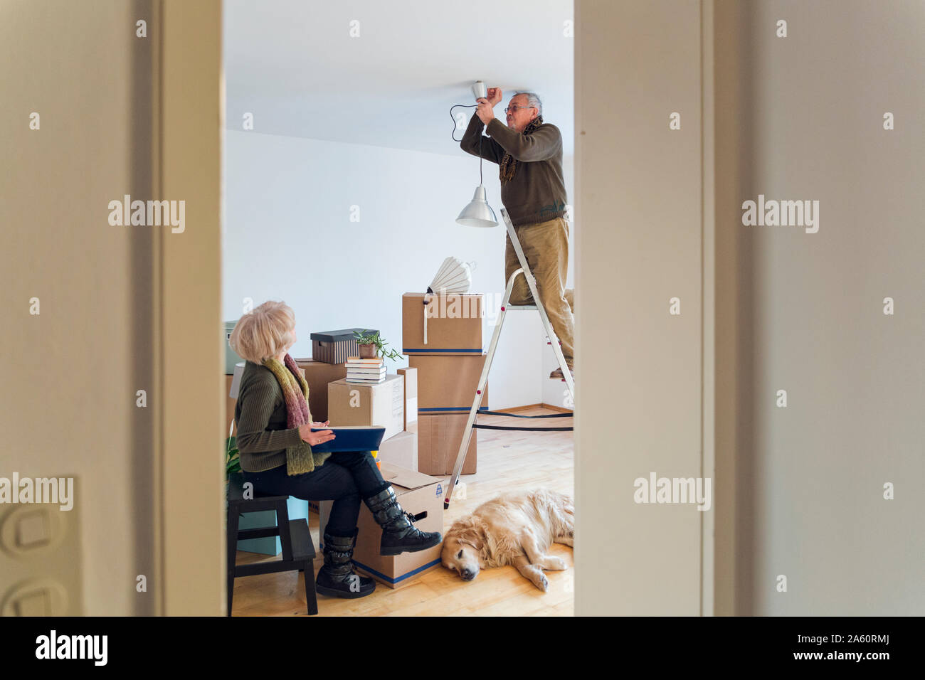 Senior couple in a new home with man mounting ceiling lamp Stock Photo ...