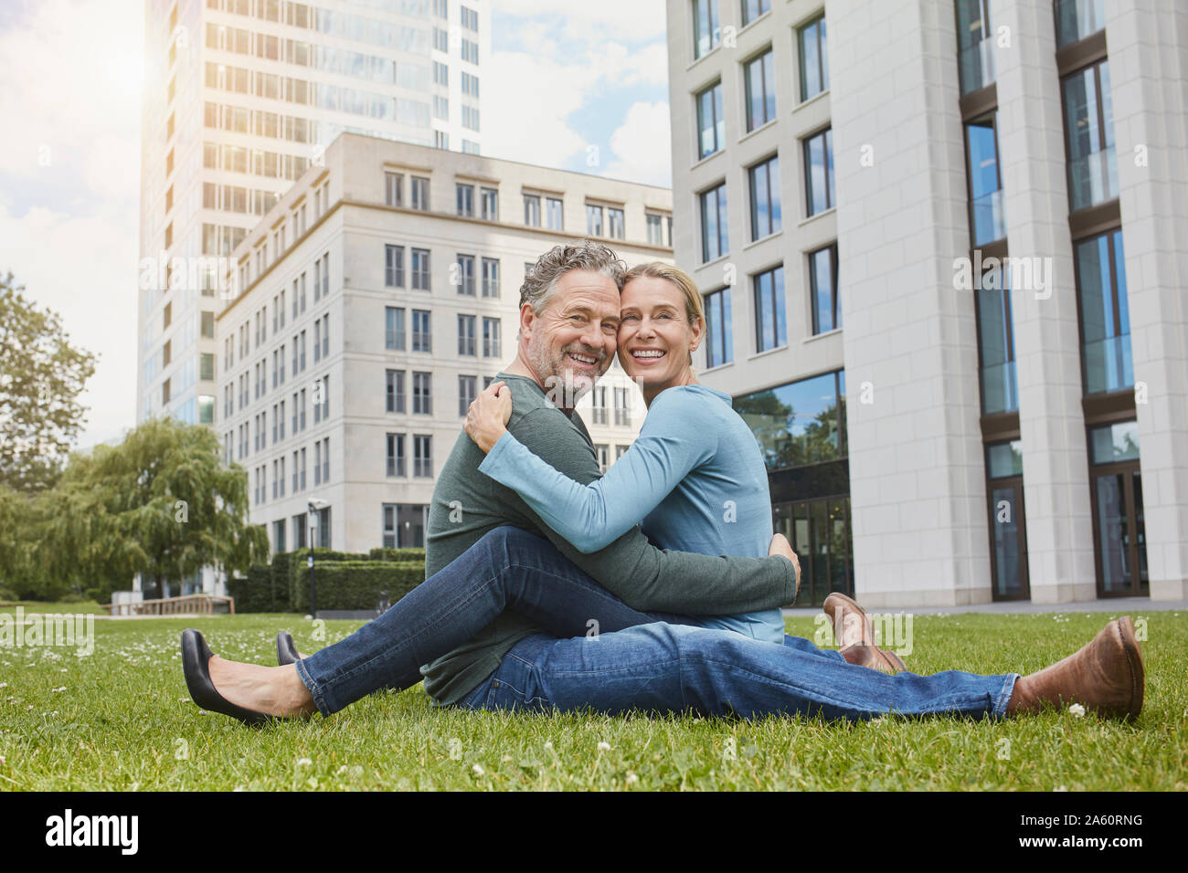 Happy mature couple sitting on lawn in the city Stock Photo