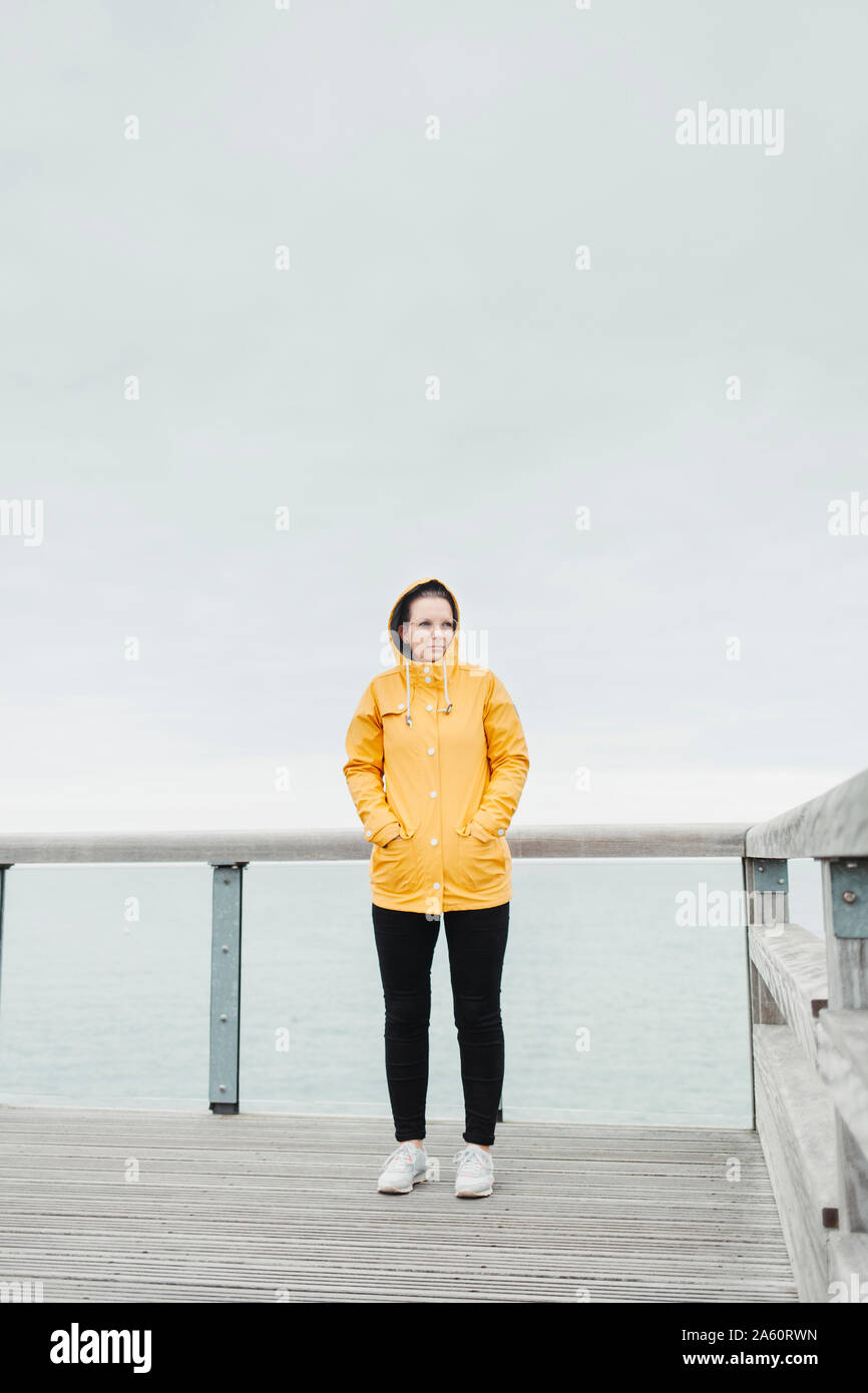 Young woman wearing yellow rain coat Stock Photo - Alamy