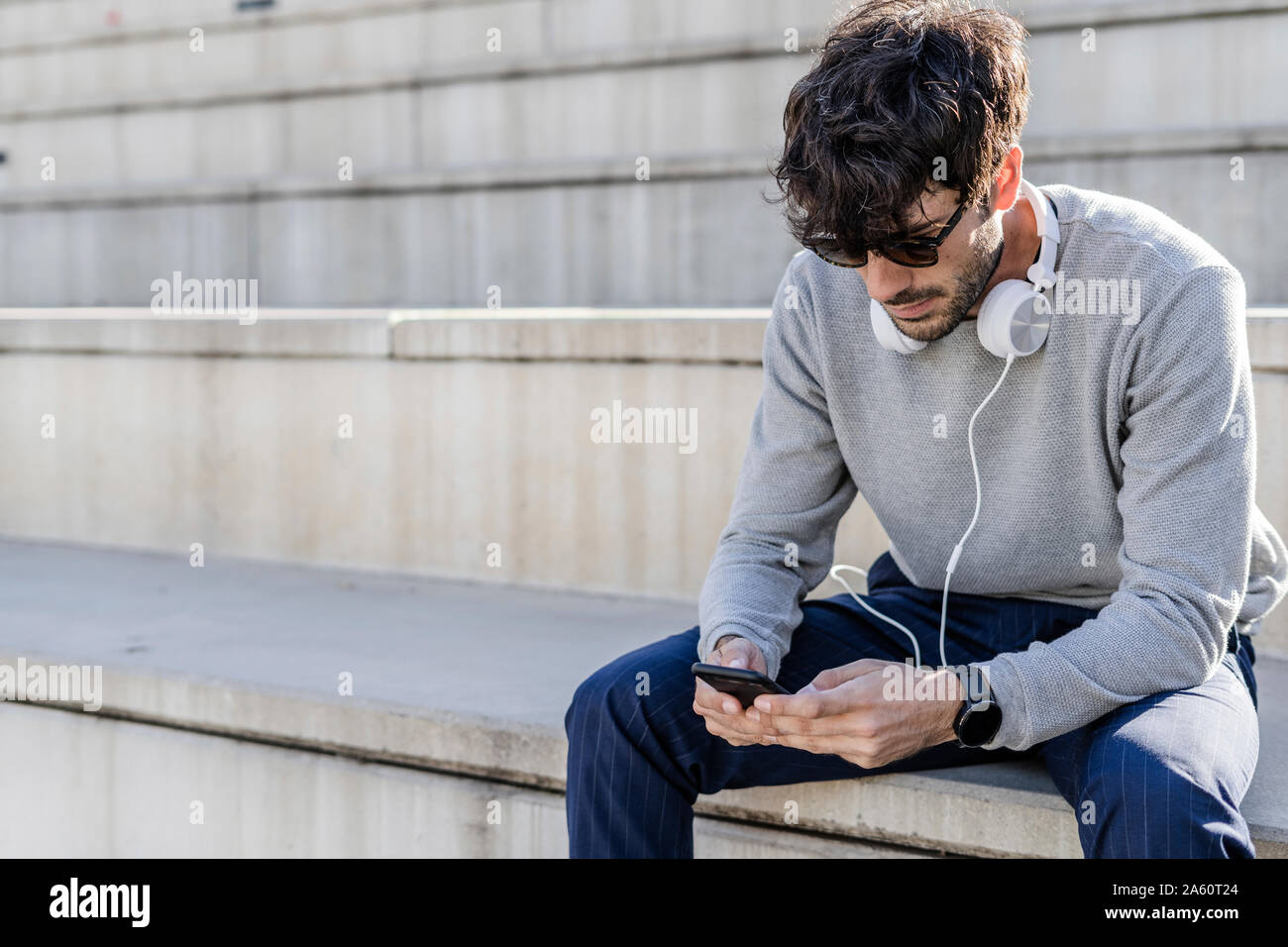 Man sitting on outdoor stairs using smartphone Stock Photo