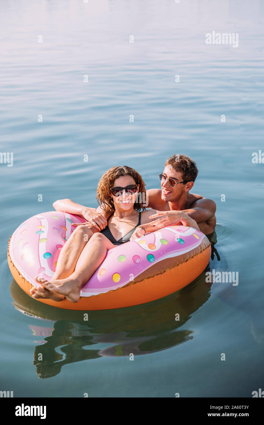 Happy young couple bathing in the sea on inflatable float in donut