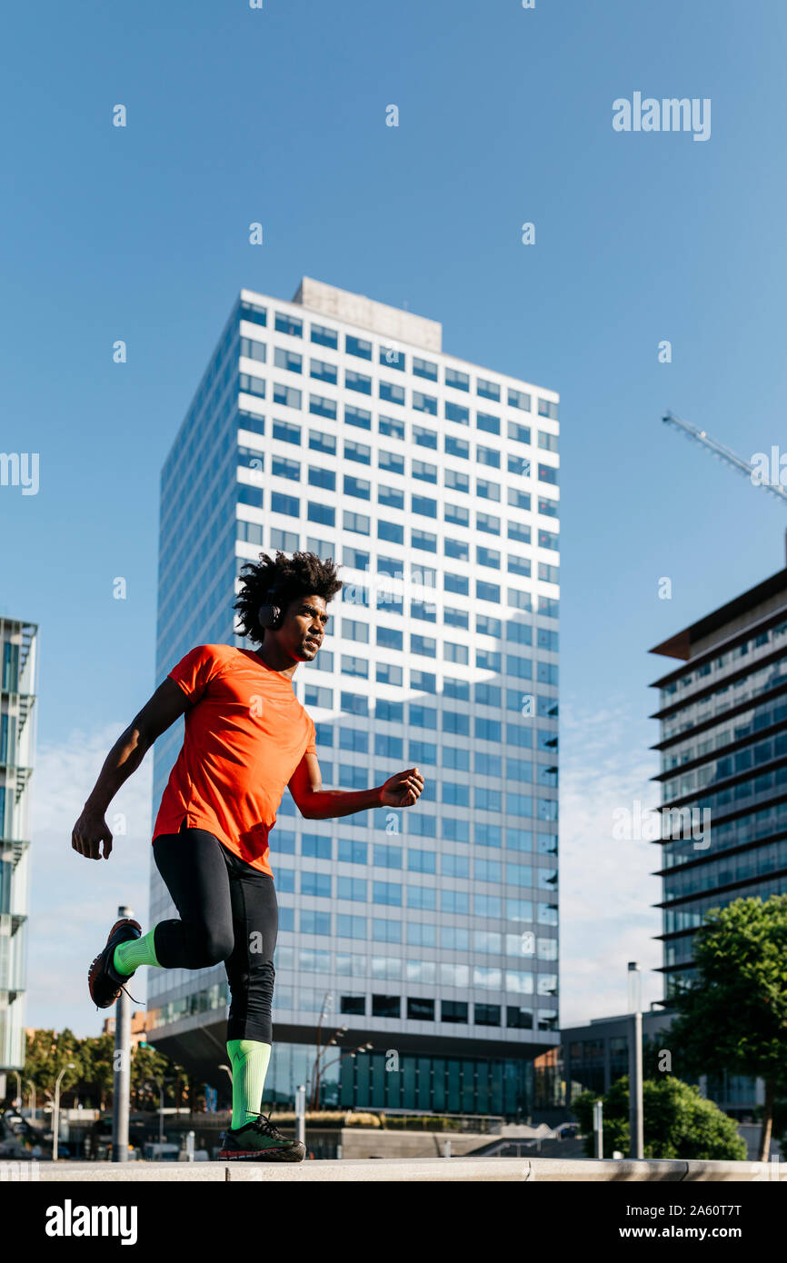 Young man jogging in the city, listening to music Stock Photo