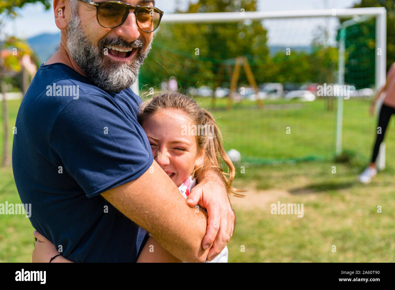 Happy father and daughter hugging on a football pitch Stock Photo