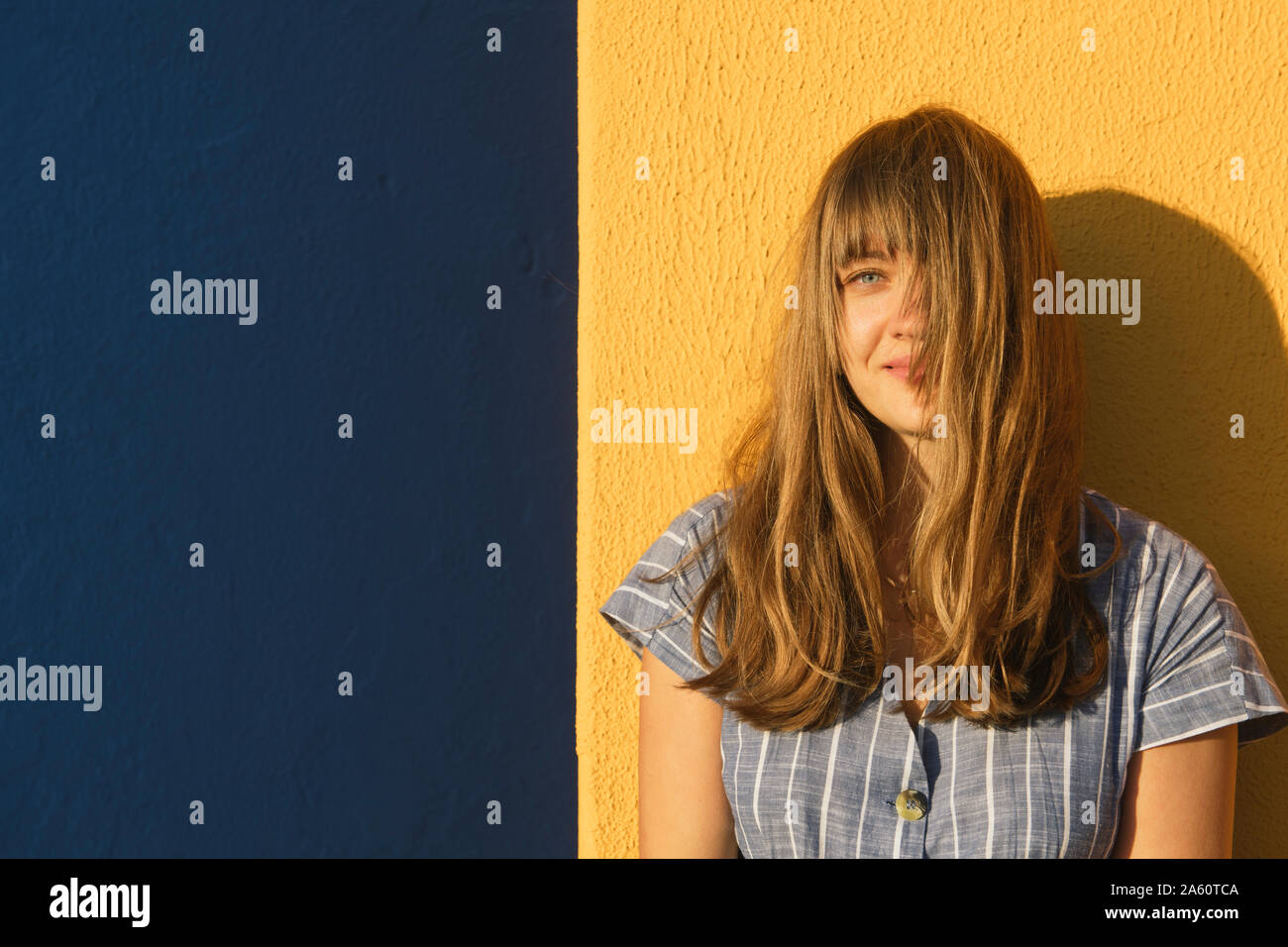 Portrait of a woman in front of yellow and blue walls Stock Photo - Alamy