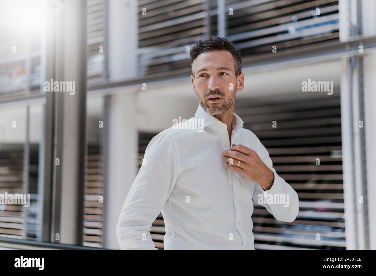 Businessman at a car park wearing white shirt Stock Photo