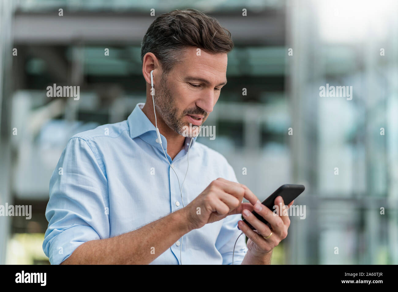 Businessman with earphones and cell phone in the city Stock Photo