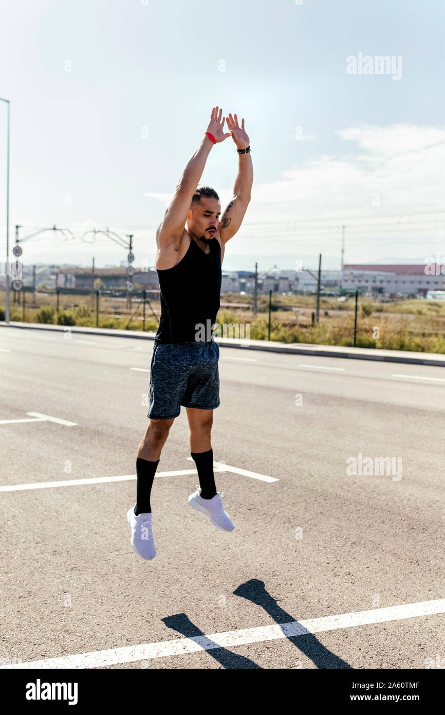 Sporty young man jumping on a road Stock Photo