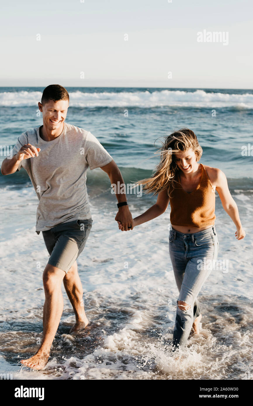 Happy young couple running at the seashore Stock Photo - Alamy
