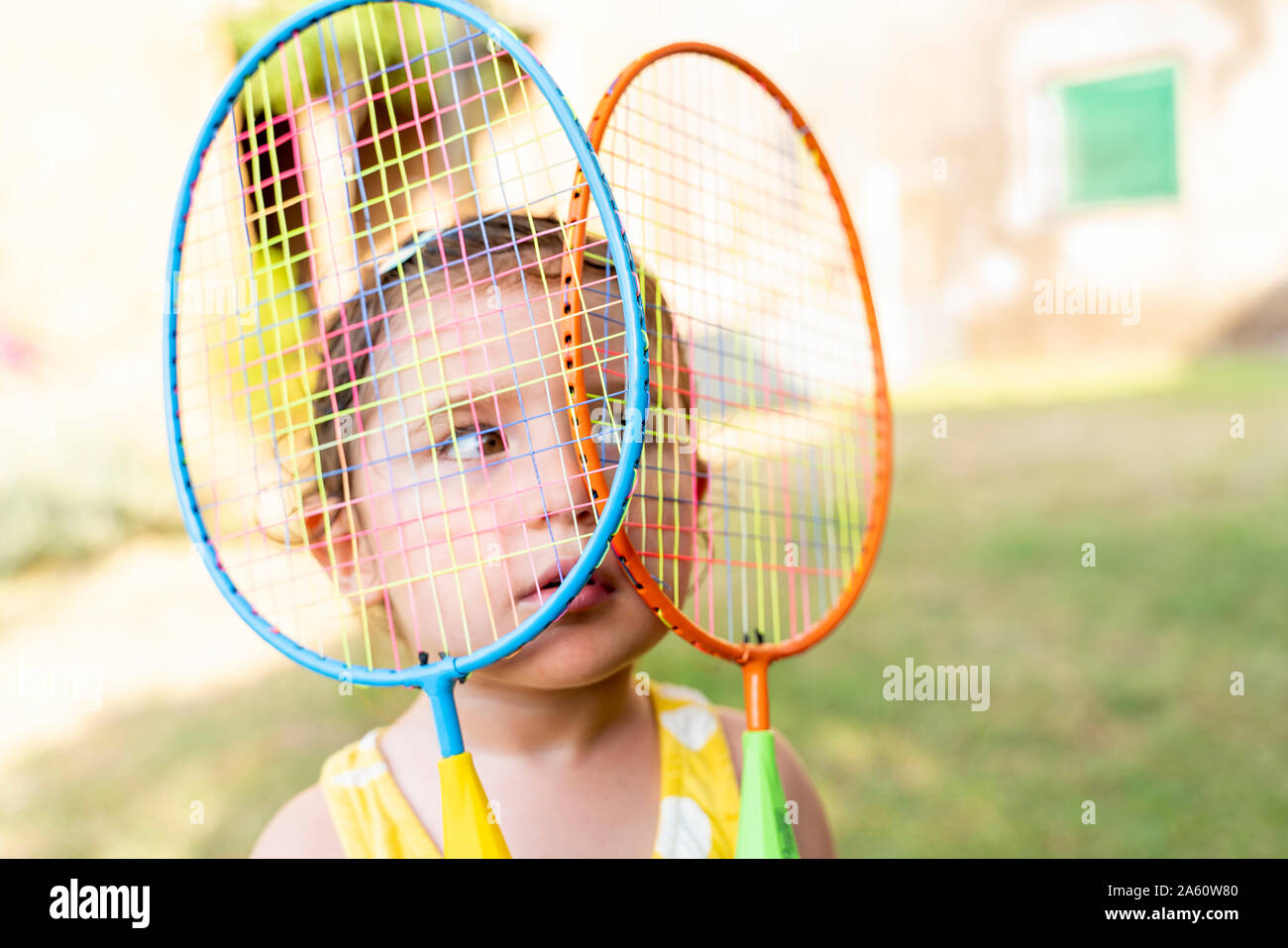 Little girl playing with colorful badminton rackets outdoors in summer Stock Photo