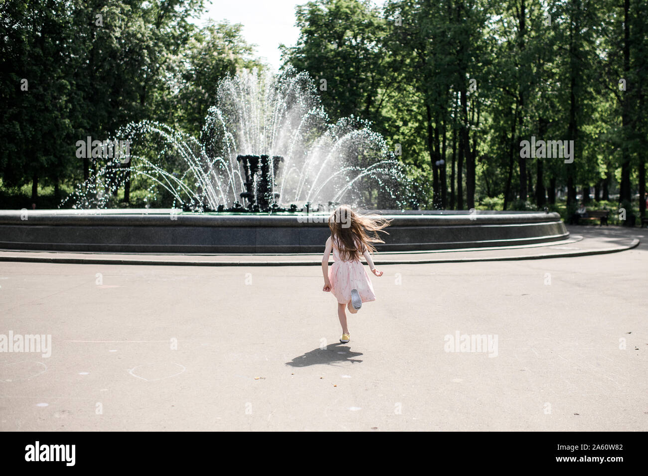 Little girl running towards a fountain Stock Photo