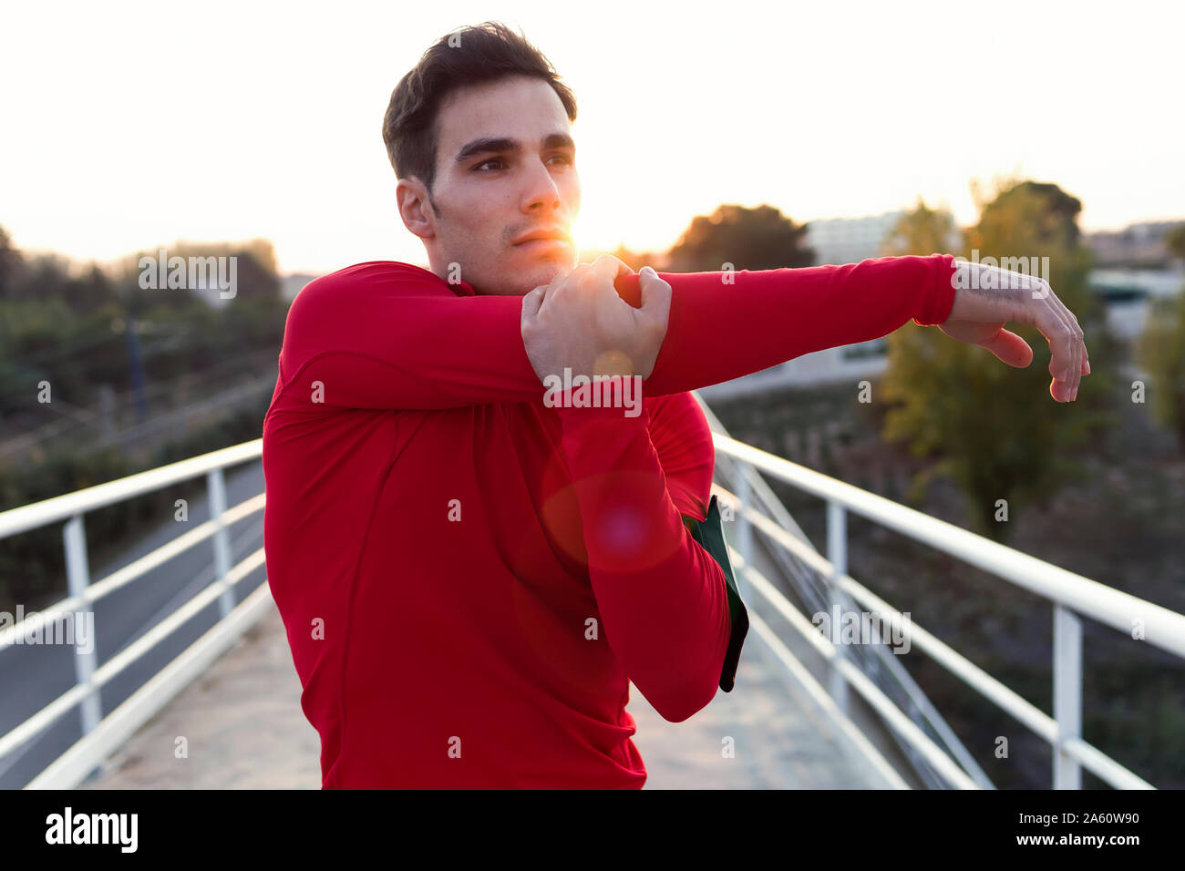Jogger stretching his arm, against evening sun Stock Photo
