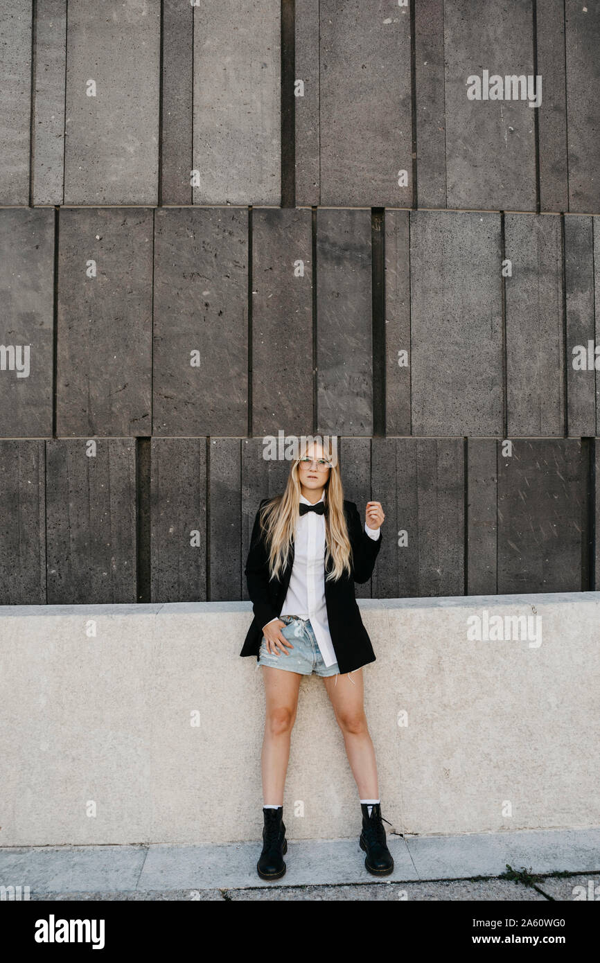 Portrait of blond young woman wearing black tie, blazer and jeans shorts, Vienna, Austria Stock Photo